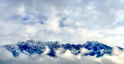 Snow covered mountains against cloudy sky