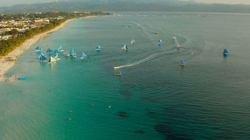 Aerial view of sailing yachts on the sandy beach of boracay island at sunset time. 