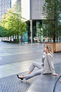 Young woman using mobile phone while standing on street in city