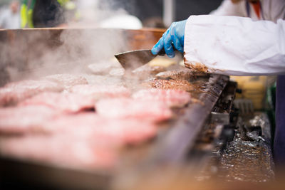 Midsection of person preparing burger at street market