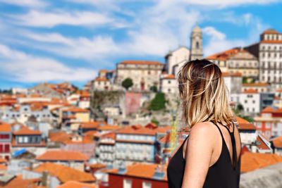 Side view of woman looking at buildings in city