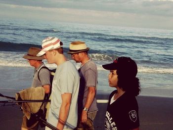 Men standing on beach against sky