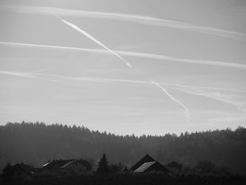 Houses and mountains against vapor trails in sky