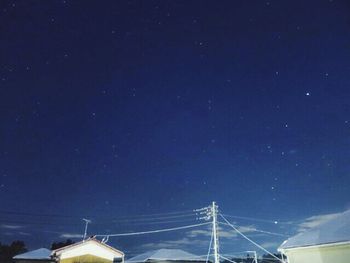 Low angle view of electricity pylon against sky at night