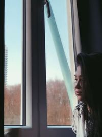 Portrait of woman looking through window