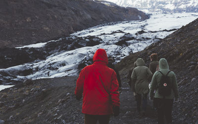 Rear view of people walking on mountain during winter