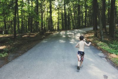 Rear view of people riding bicycle on road in forest