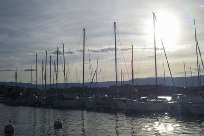 Sailboats moored at harbor against sky during sunset