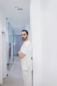 Doctor with arms crossed standing in corridor at hospital