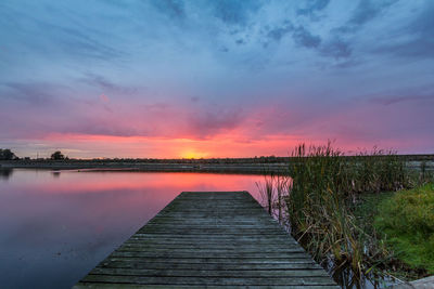 Pier over lake against sky during sunset