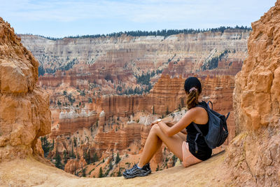 Side view of man on rock by mountains