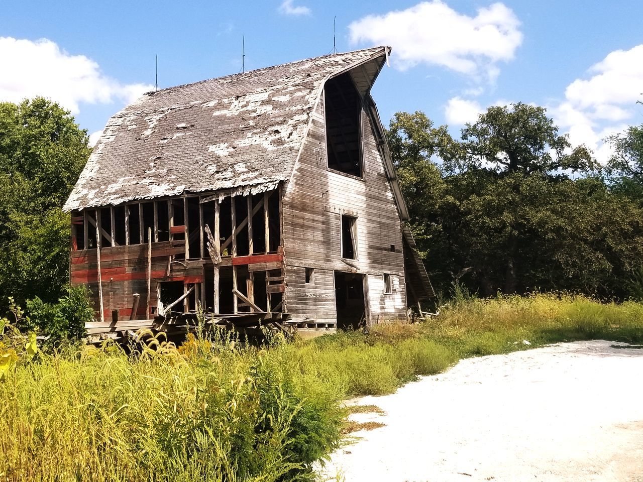 OLD HOUSE ON FIELD BY TREES AGAINST SKY