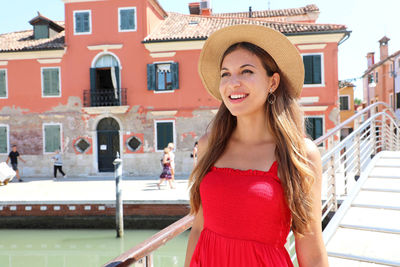 Smiling young woman standing against building