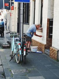 Man with bicycle on street against buildings