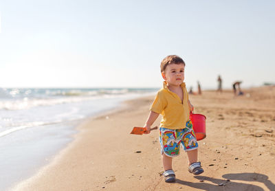 Cute boy carrying bucket at beach