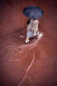 Rear view of woman walking with umbrella