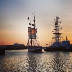 Sailboats in sea against sky during sunset