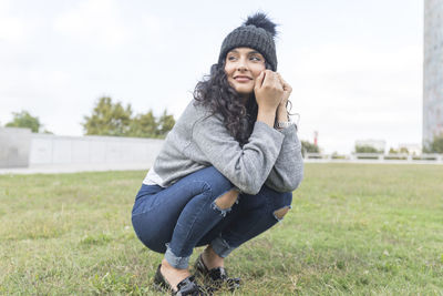 Smiling woman crouching on field