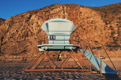 Lifeguard hut against rocky mountain at sandy beach