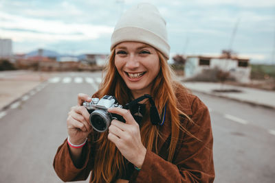 Portrait of smiling young woman holding camera