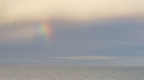 Scenic view of rainbow over sea against sky