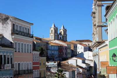 Low angle view of buildings in city against clear blue sky