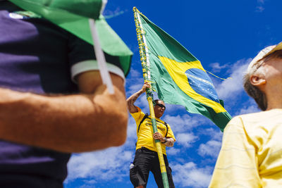 Low angle view of woman standing against blue sky