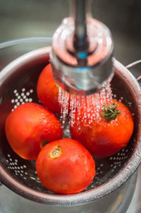 High angle view of tomatoes in strainer under sink faucet
