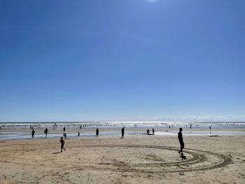 People on beach against blue sky