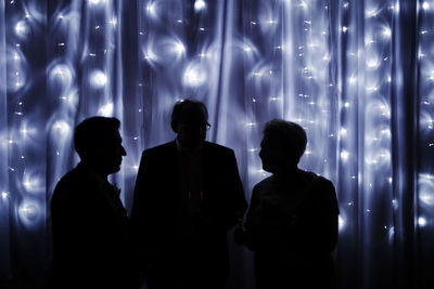 Silhouette people standing against illuminated lights