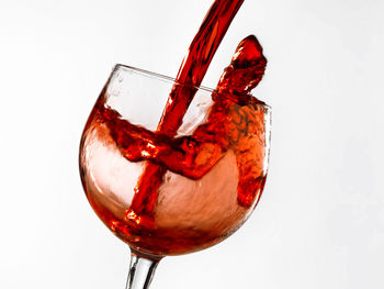 Close-up of wineglass on glass against white background