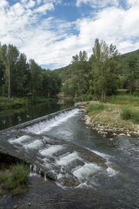 Scenic view of waterfall against sky