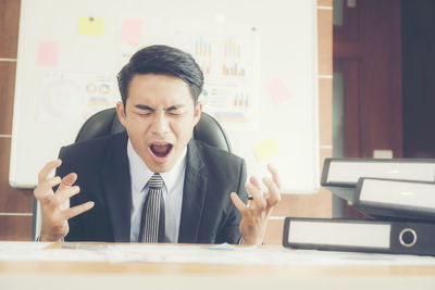 Frustrated businessman screaming while sitting in office