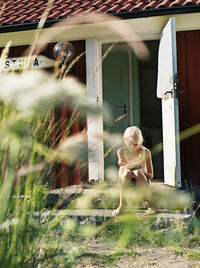 Girl eats breakfast on stairs in front of cottage