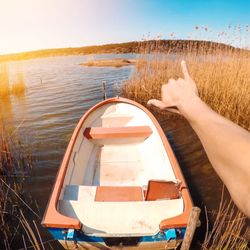 Close-up of hand on boat in sea against clear sky