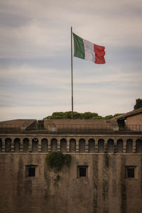 Flag against built structure and bridge against sky