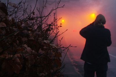 Rear view of silhouette woman standing against sky during sunset