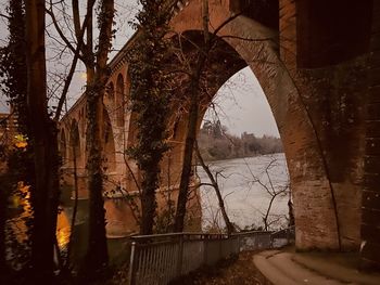 Arch bridge over river against sky