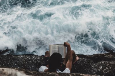 High angle view of cropped man reading book