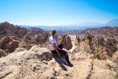 Man sitting on rock against mountains