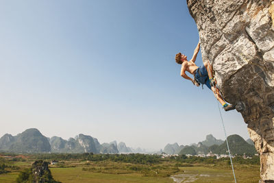 Male climber pulling up on overhanging rock in yangshuo / china