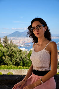 Portrait of young woman wearing eyeglasses against sky