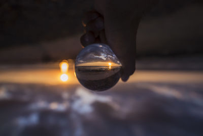 Close-up of illuminated light bulb against sky