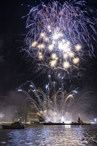 Firework display over river against sky