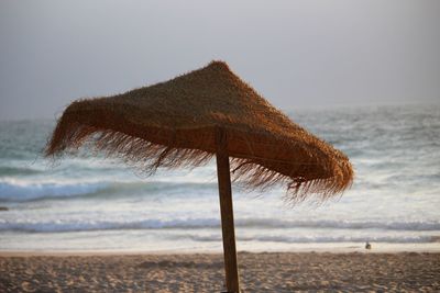 Thatched roof on beach against clear sky