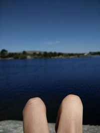 Low section of legs against calm lake