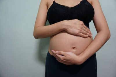 Midsection of woman touching wall