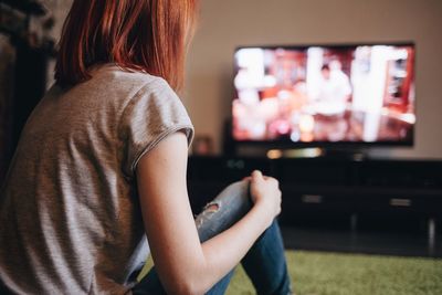 Close-up of young woman watching tv