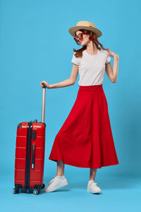 Woman wearing hat standing against blue background