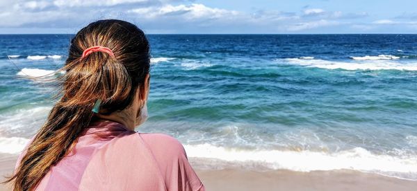 Rear view of woman looking at sea against sky